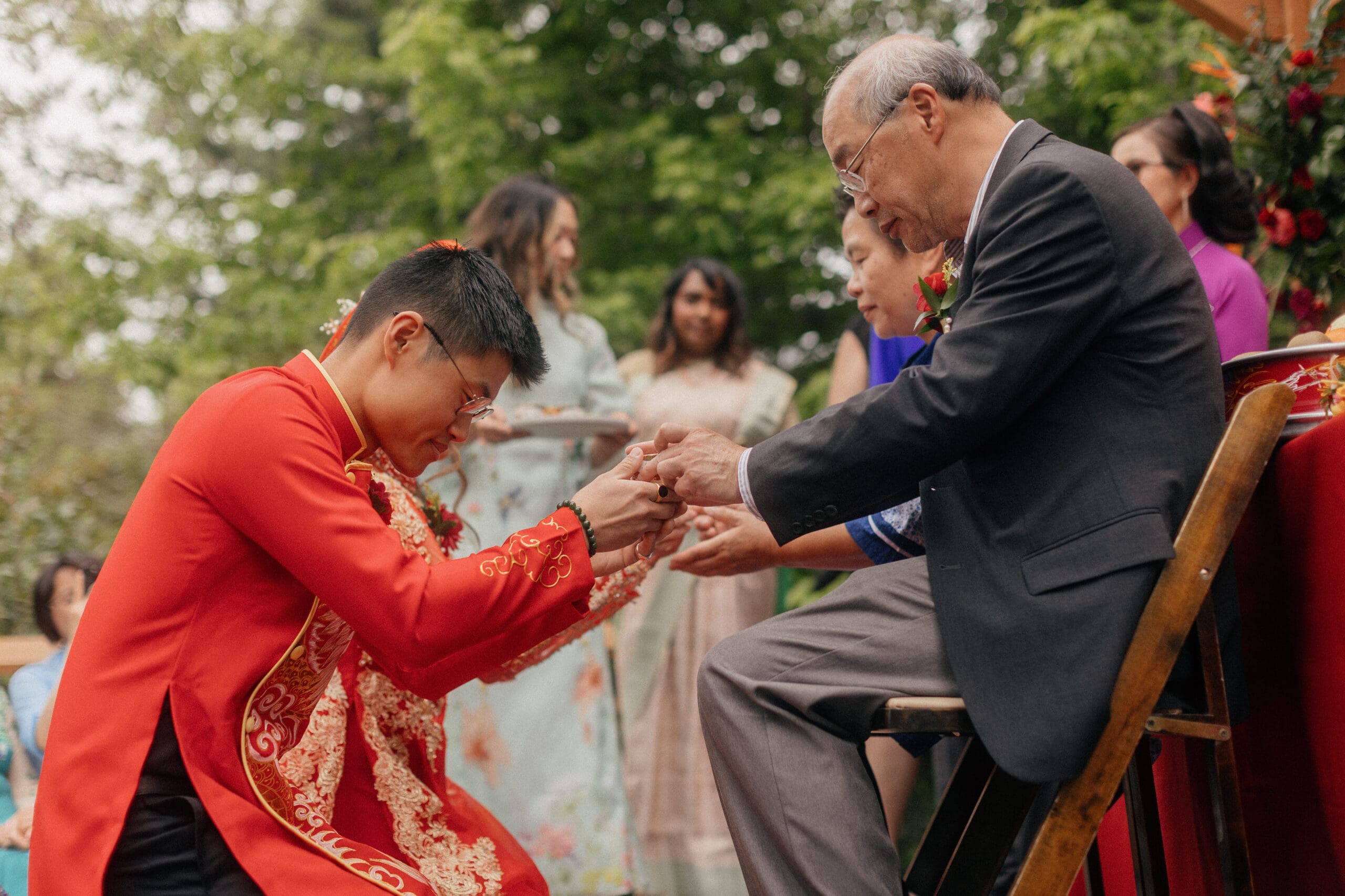 Couple kneeling during their Chinese-Vietnamese tea ceremony at Chase Mill at Tracy Aviary, honoring their parents with traditional gestures of respect.